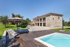 a house with a swimming pool and an umbrella at Casa da Tomada - Minho's Guest in Braga