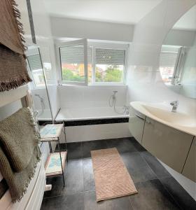 baño con bañera y lavamanos y 2 ventanas en A la villa du voyageur - proche Europa Park, Strasbourg et Colmar en Sélestat
