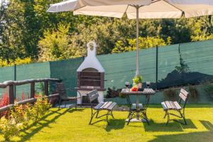 un patio trasero con mesa, sillas y sombrilla en Villa Kasztelan, en Ustrzyki Dolne