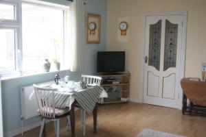 a dining room with a table and a tv and a door at Swallows Rest in Annascaul