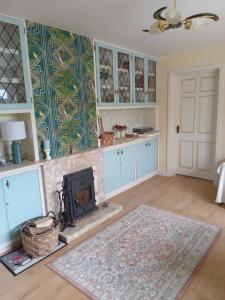 a living room with a fireplace and a kitchen at Swallows Rest in Annascaul