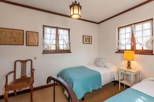 1 dormitorio con 2 camas, silla y ventanas en Casa do Monte - Minho's Guest en Cabanelas