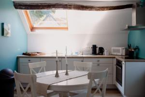 eine Küche mit einem Tisch und Stühlen sowie einem Fenster in der Unterkunft Logis Le P'tit Rouillon au Rythme de la Meuse in Annevoie-Rouillon