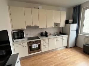 a kitchen with white cabinets and a sink and a refrigerator at Cool Schönbrunn Apt 2BR in Vienna