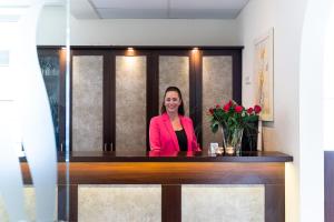 a woman is standing at a reception desk at Hotel Banter Hof in Wilhelmshaven