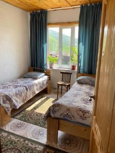 1 Schlafzimmer mit 2 Betten, einem Fenster und einem Stuhl in der Unterkunft Bulak in Tar-Suu