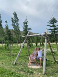 zwei Personen, die in einer Spielstruktur auf einem Feld sitzen in der Unterkunft Bulak in Tar-Suu