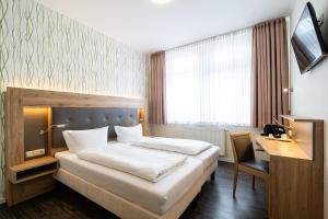 ヴィルヘルムスハーフェンにあるHotel Banter Hofのベッドとデスクが備わるホテルルームです。