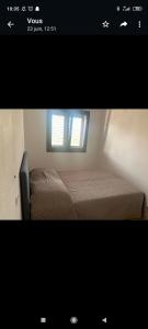 um pequeno quarto com uma cama e uma janela em Appartement F2 meublé em Loculi