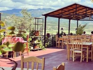 a restaurant with tables and chairs and mountains in the background at Bujtina Te Xhako in Përmet