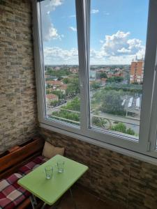 a table and two glasses in a room with two windows at Oscar's Central Apartment in Timişoara
