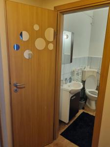 a bathroom with a toilet and a wooden door at Oscar's Central Apartment in Timişoara