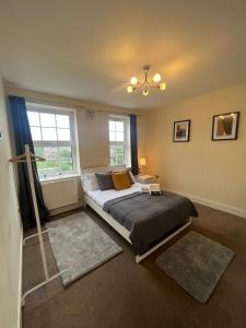 a bedroom with a large bed and two windows at Stunning Wembley Stadium Flat in London