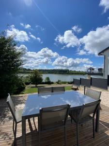 a table and chairs on a deck with a view of a lake at Le chalet de la liez in Peigny