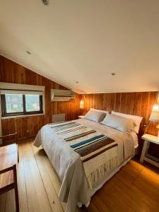 a bedroom with a large bed and wooden walls at Hotel Boutique Casa&Alma in Puerto Varas