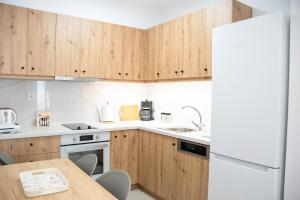 a kitchen with wooden cabinets and a white refrigerator at Andy's Plaza in Agia Pelagia