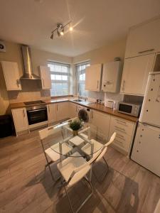 a kitchen with a glass table and two chairs at Stunning Wembley Stadium Flat in London