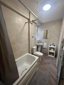 a bathroom with a tub and a toilet and a sink at Stunning Wembley Stadium Flat in London