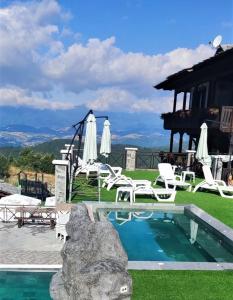 une piscine avec des chaises blanches et une maison dans l'établissement Leshtenski Perli, à Leshten