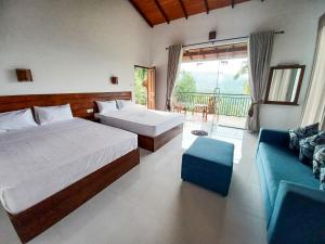 a bedroom with two beds and a blue couch at Ella Panorama Villa in Ella