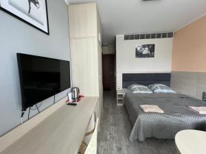a bedroom with a bed and a flat screen tv at BARBIE & KEN - Apartamenty na ostatnim piętrze w Dominikana Resort & SPA Sianożęty in Sianozety