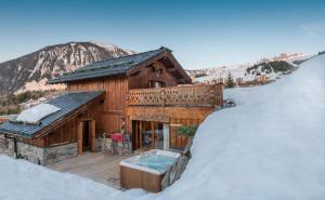 a log cabin with a hot tub in the snow at Chalet Barragiste in Courchevel