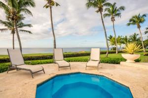 una piscina con 2 sillas, palmeras y el océano en Sunny vacation Villa No 67, en San Rafael del Yuma