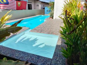 パンタイチェナンにあるImpiana homestay langkawiの庭の青い水のスイミングプール