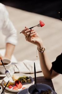 a woman holding a piece of a strawberry on top of a table at Boutique Hotel NOAE by Emerald Stay in Oletta +13 photos