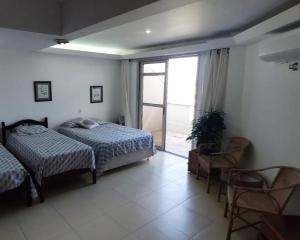 a bedroom with two beds and a sliding glass door at Triplex Cabo Frio in Cabo Frio