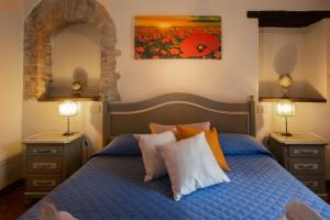 a bedroom with a blue bed with pillows and a painting at Locanda Il Porcellum in Bagno Vignoni