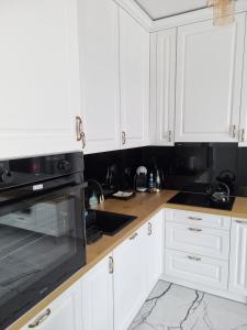 a kitchen with white cabinets and a black microwave at ManuSite in Łódź