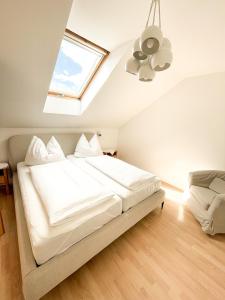 a bedroom with a large white bed with a skylight at Im Ramsen - Familie Baier in St. Wolfgang