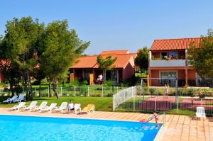 a person sitting in lawn chairs next to a swimming pool at Résidence Goélia Cap Bleu in Carro