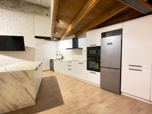 una cocina con armarios blancos y electrodomésticos de acero inoxidable en Manresa industrial home en Manresa