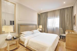 um quarto com uma cama, uma secretária e uma janela em Palmyard Hotel em Manama