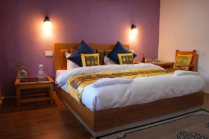 1 dormitorio con 1 cama grande y paredes moradas en THE RIVERSIDE RESORT Hunder en Leh