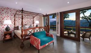 a bedroom with a bed and a chair and a window at The Elephant Stables in Kandy