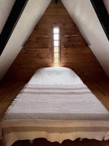 a bed in a wooden room with a window at Habitación cálida y acogedora a pasos del mar in Buchupureo