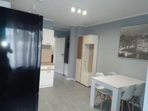 Il comprend une cuisine et une salle à manger avec une table et des chaises blanches. dans l'établissement Noclegi na Heweliusza, à Sanok