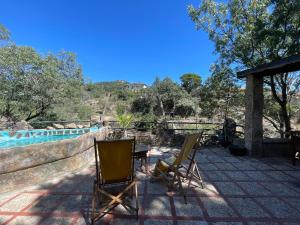 2 sillas y una mesa en un patio junto a la piscina en Casa Fidelina III Miraflores de la Sierra, en Miraflores de la Sierra