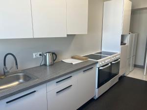 a kitchen with white cabinets and a sink at Worker hotel ALEJPARKS in Valmiera