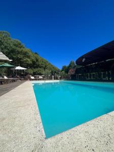 uma grande piscina azul num resort em Cabañas en el Bosque a 5 minutos del mar - Estancia CH em Punta del Este