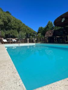 a large blue swimming pool with a mountain in the background at Cabañas en el Bosque a 5 minutos del mar - Estancia CH in Punta del Este