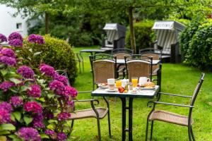 a table and chairs with food and drinks and flowers at Wilhelms HAVEN HOTEL in Wilhelmshaven