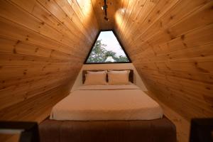 a bed in a wooden room with a window at Kompleksi Turistik DEA in Shkodër