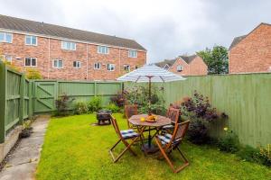 a table and chairs with an umbrella in a yard at Luxury 3-bed house - Rothwell Gardens - 10mins from Leeds city centre in Rothwell