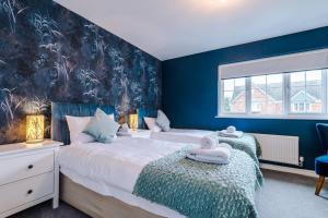 two beds in a bedroom with blue walls at Luxury 3-bed house - Rothwell Gardens - 10mins from Leeds city centre in Rothwell