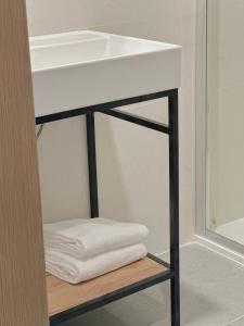 a white sink and towels on a shelf in a bathroom at Apartamentos Lidar in Bilbao