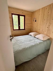 Cama en habitación de madera con ventana en Chalet la parenthèse, en Le Tholy